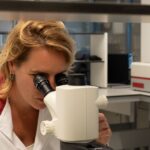 anne kienhuis kijkt door de microscoop in het lab