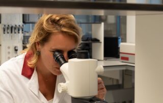 anne kienhuis kijkt door de microscoop in het lab